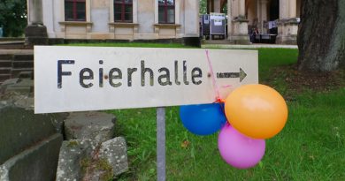 Feierhalle-Schild auf dem Friedhof mit Luftballons dran