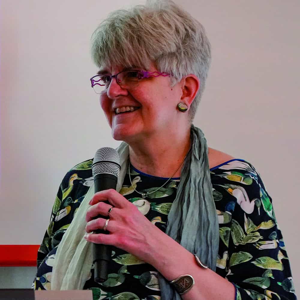 Porträtfoto Friederike Ursprung mit Mikro beim Symposium als Moderatorin