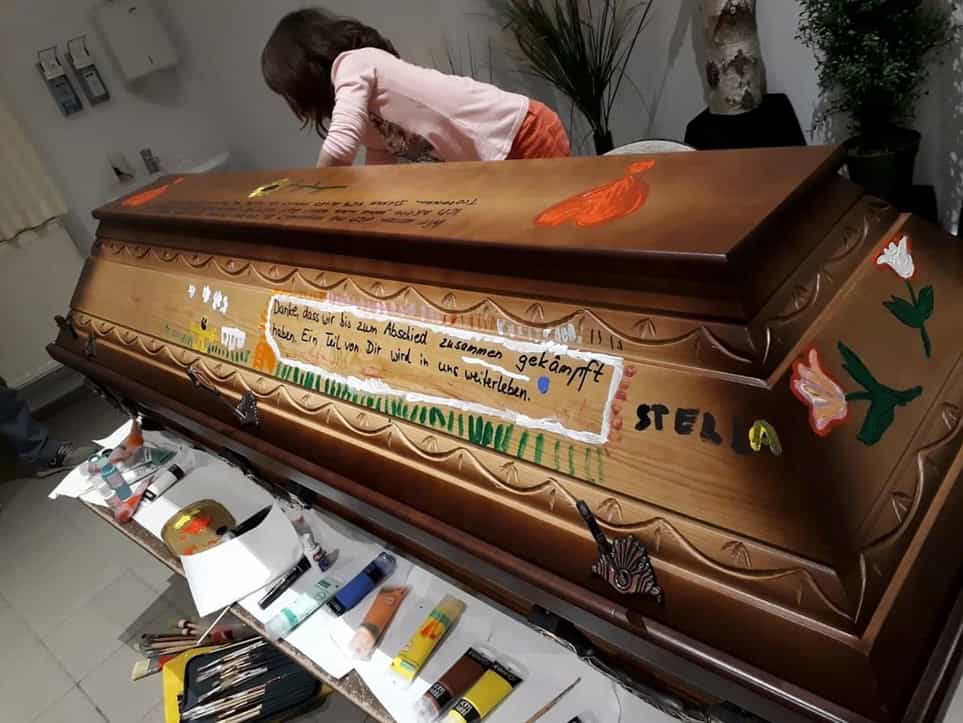 Kind bemalt einen Sarg.