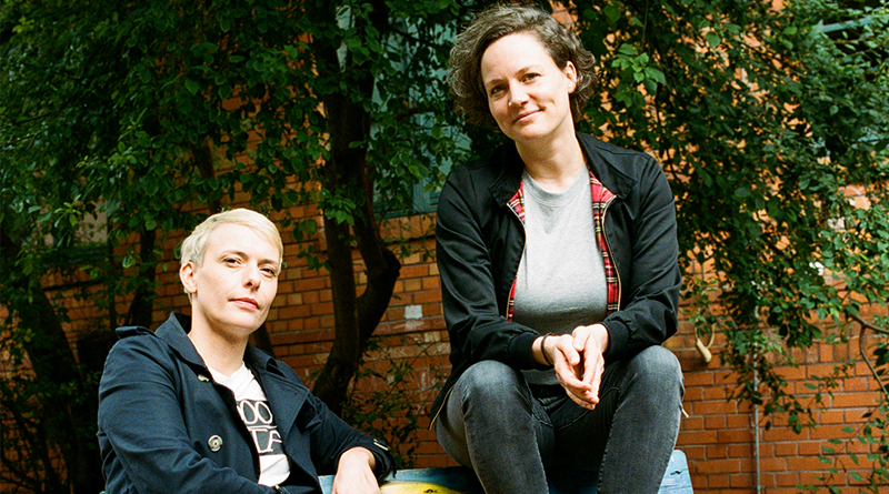 Porträtfoto Susann Brückner und Caroline Kraft, beide sitzen draußen auf einer Bank