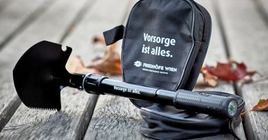 Foto schwarze Klappschaufel mit der Aufschrift „Vorsorge ist alles” als Merchandise, dahinter die Schaufel-Verpackung mit gleicher Aufschrift