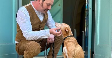Eric Wrede hockt neben seinem rot-braunen Hund und grault dessen Kinn, beide schauen sich an und lächeln, Foto: privat