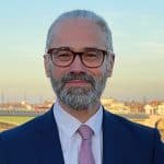 Porträtfoto Prof. Dr. Dr. Tade Spranger im blauen Anzug vor Fluß und Häusern