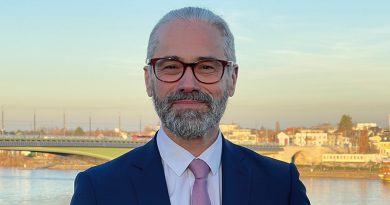 Porträtfoto Prof. Dr. Dr. Tade Spranger im blauen Anzug vor Fluß und Häusern