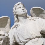 Foto von Lara Schink, Engelskulptur auf dem Friedhof vor blauem Himmel