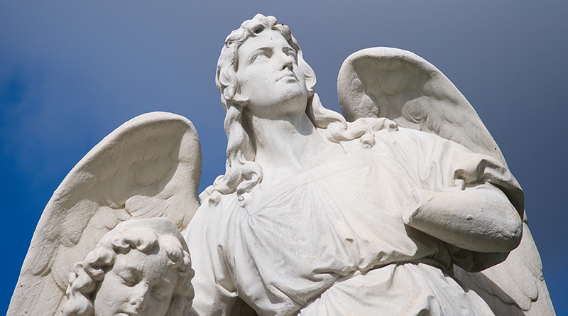 Foto von Lara Schink, Engelskulptur auf dem Friedhof vor blauem Himmel