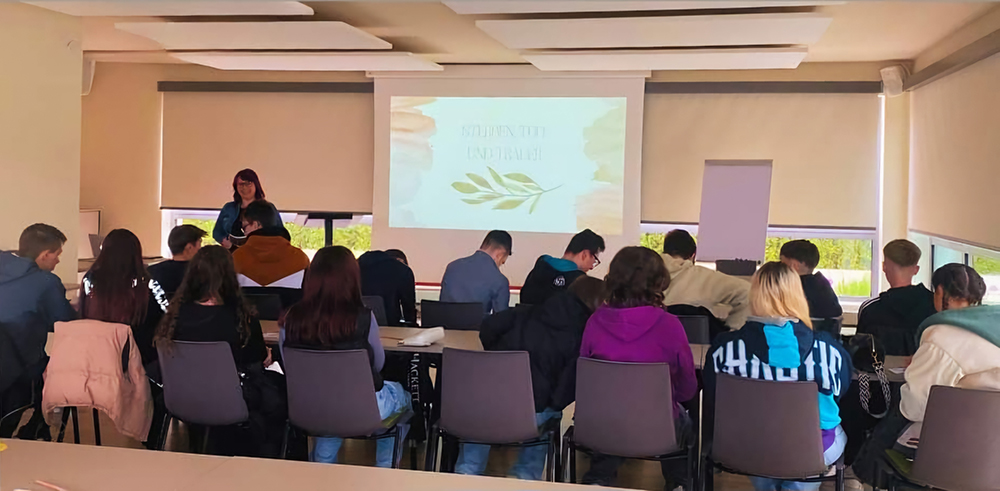 Innenraum Zentrum für Endlichkeitskultur, Jeanette Heller steht vor einer Klasse und hält einen Vortrag