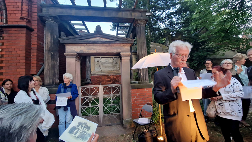 Mann mit Mikro auf einer Veranstaltung auf dem Friedhof