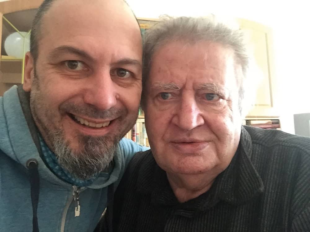 Foto: Denis und Peter haben ihre Köpfe aneinander gelehnt und lächeln beide in die Kamera