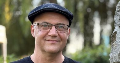 Porträtfoto Dirk Rotzsch von Jörn Rohrberg, Dirk steht neben einer Steinskultur und lächelt in die Kamera, er trägt ein Shirt von The Cure