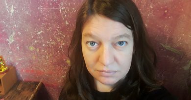 Portraitfoto Juliane Streich, Nahaufnahme, Juliane schaut von unten nach oben in die Kamera, lila-dunkelrosaer Hintergrund, indoor, Foto: privat