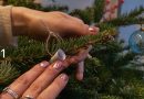 Weihnachtsbaum wird geschmückt, Hand am Baum ist sichtbar, die gerade etwas befestigt