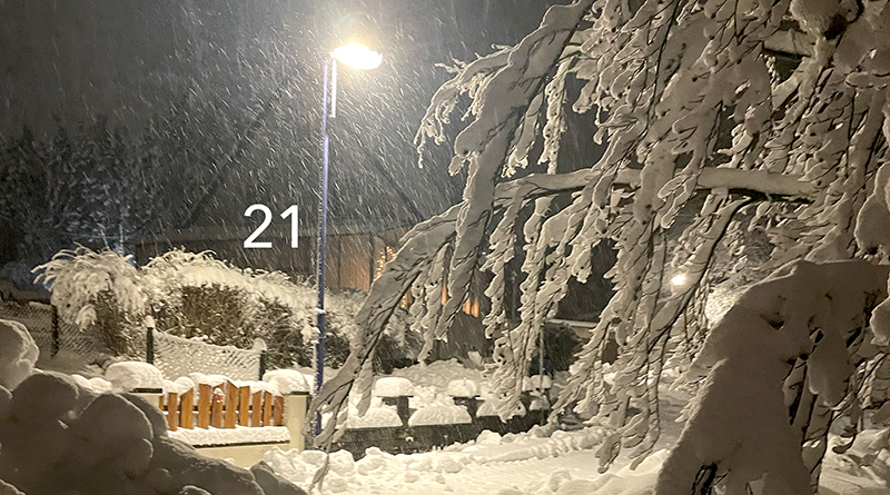 Verschneite Nacht im Dezember in einem Dorf, Straßenlaterne leuchtet